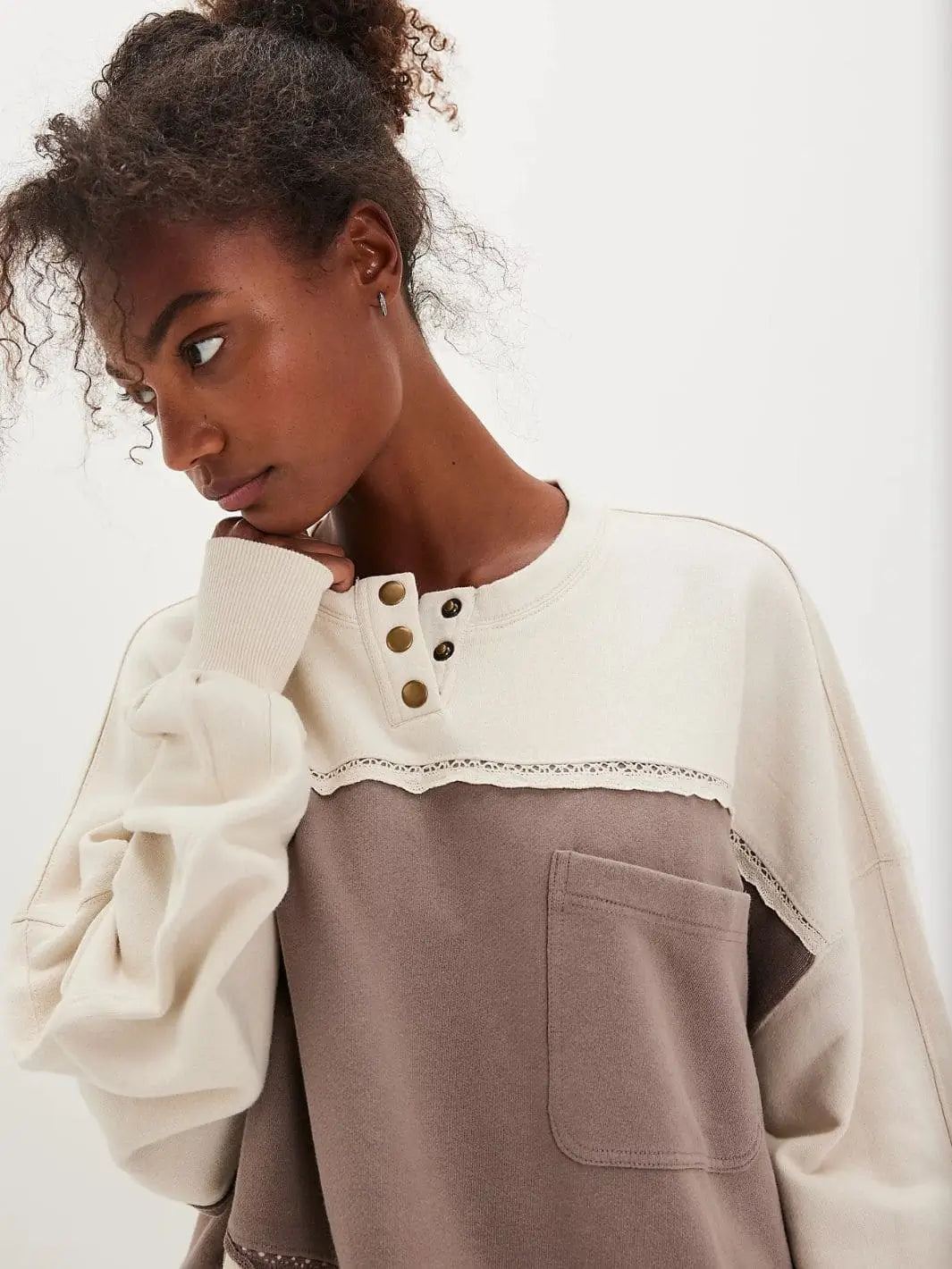 A close-up shot focuses on the henley button neckline, front pocket, and lace trim details of the Free People Strawberry Sweatshirt - Summer Sand Combo | Twentyseven Toronto