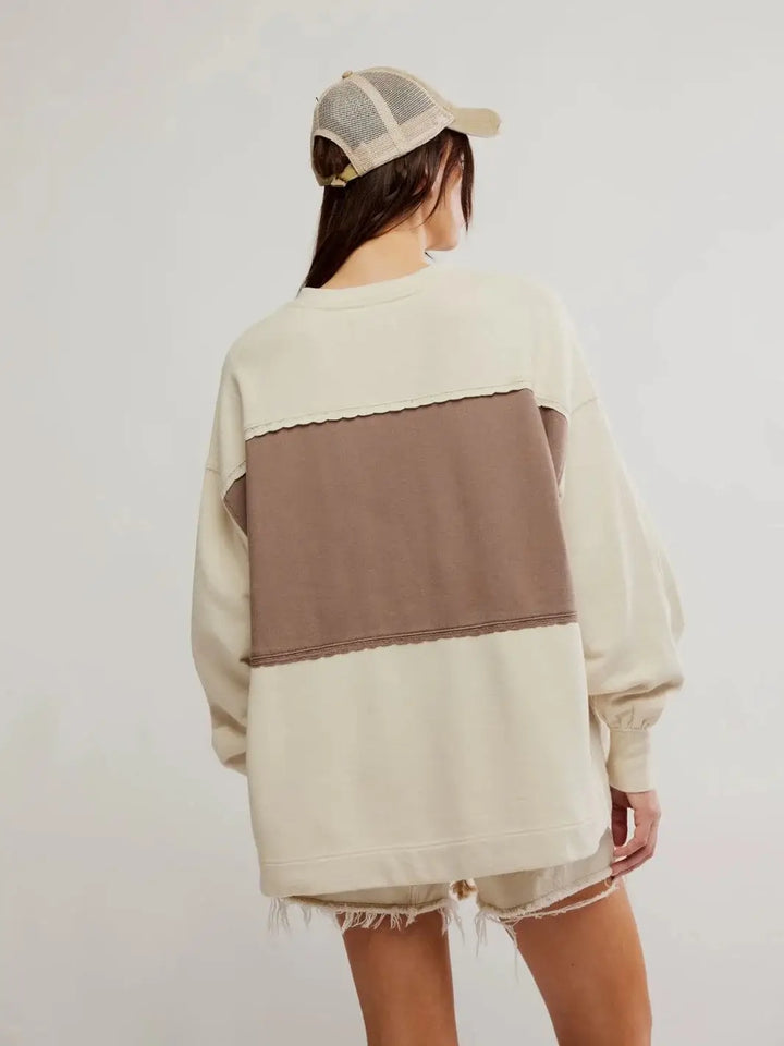 Back view of a model wearing a mesh trucker cap and showcasing the oversized length of the Free People Strawberry Sweatshirt - Summer Sand Combo | Twentyseven Toronto