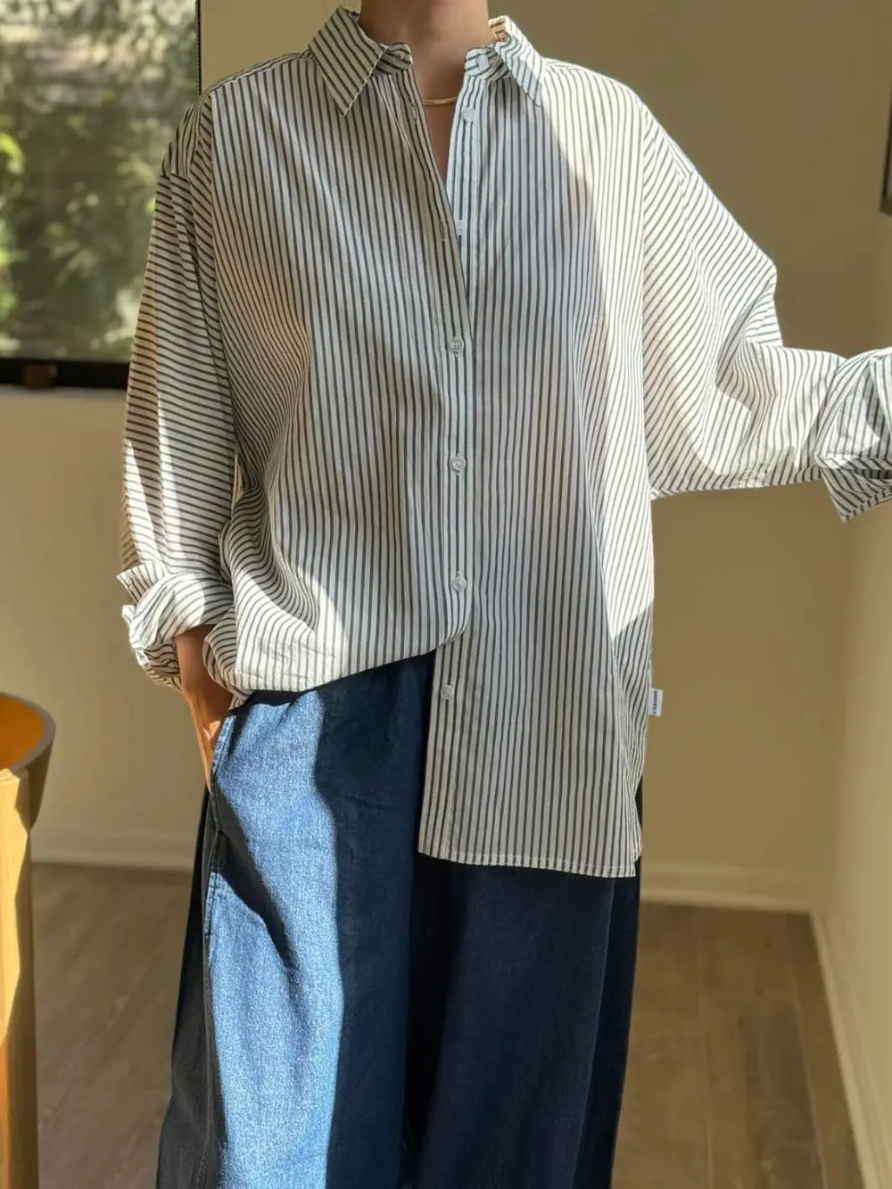 Person wearing a Striped 'Light Weight Owen Shirt' in 'Denim Stripe On White' and blue pants from Le Bon Shoppe in an indoor setting | Twentyseven Toronto