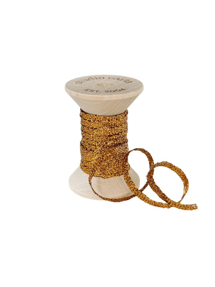 Studio Carta Metallic Braided Ribbon in Amber wrapped around a wooden spool with ribbon unfurled | Twentyseven Toronto