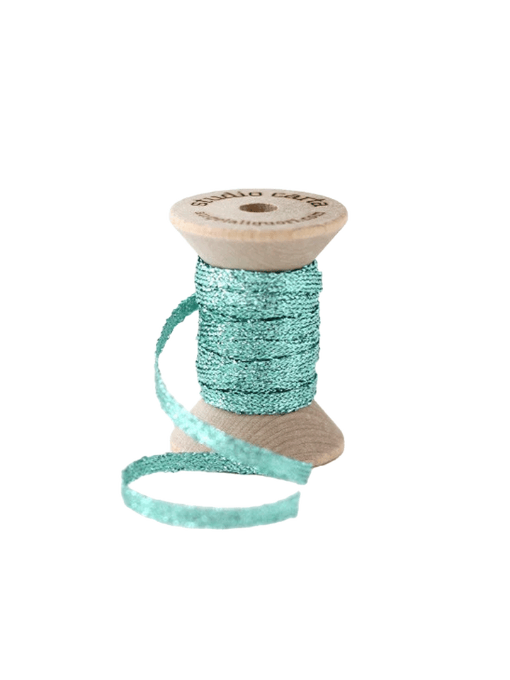 Studio Carta Metallic Braided Ribbon in Aquamarine wrapped around a wooden spool with ribbon unfurled | Twentyseven Toronto