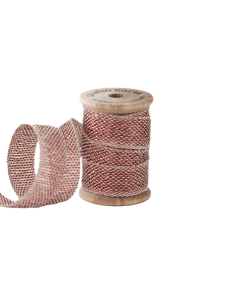 Studio Carta Metallic Loose Weave Ribbon in Natural/Copper wrapped around a wooden spool with ribbon unfurled | Twentyseven Toronto