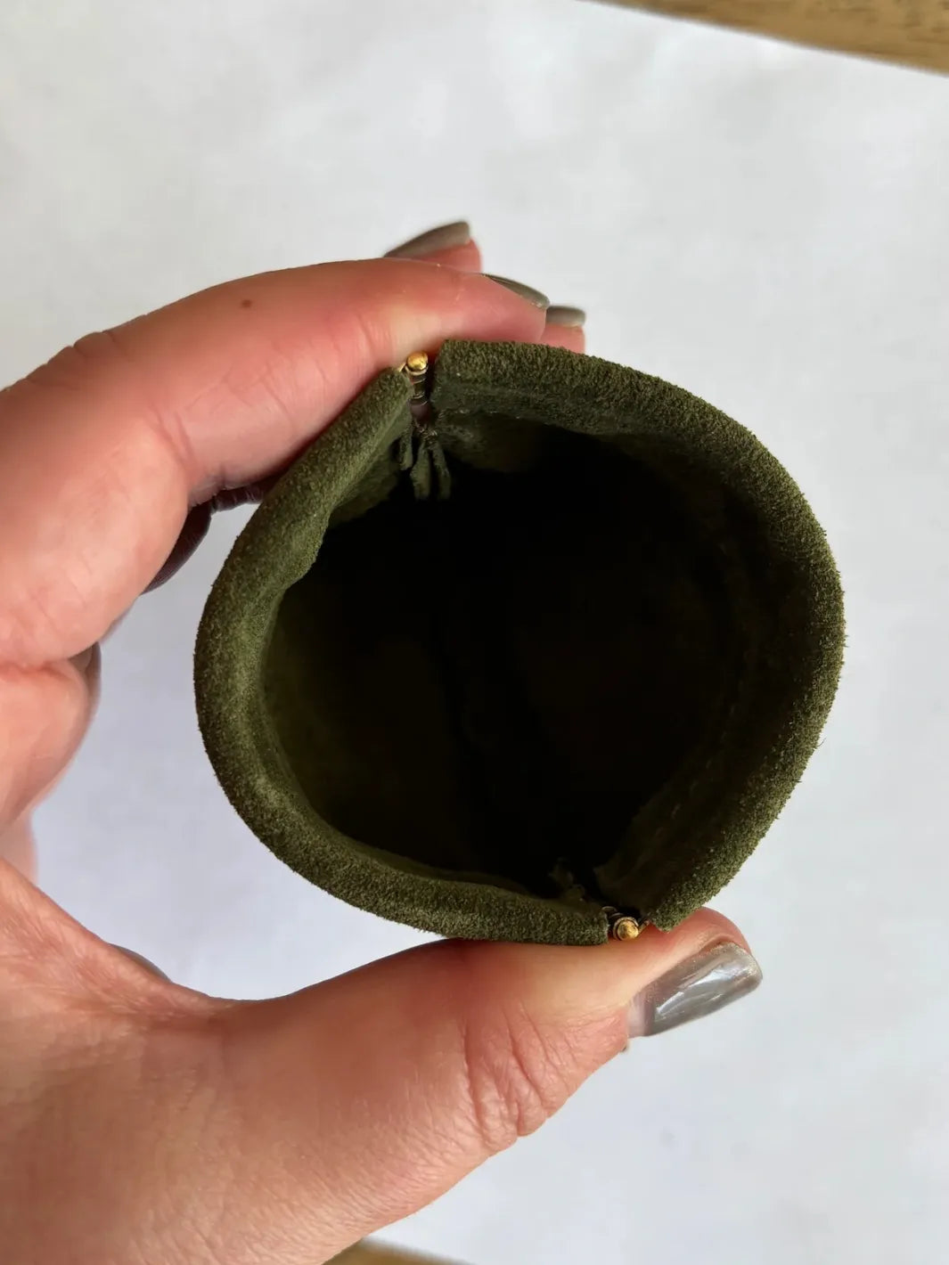Hand holding a small dark green coin pouch in 'Forest Green' against a white background | Twentyseven Toronto