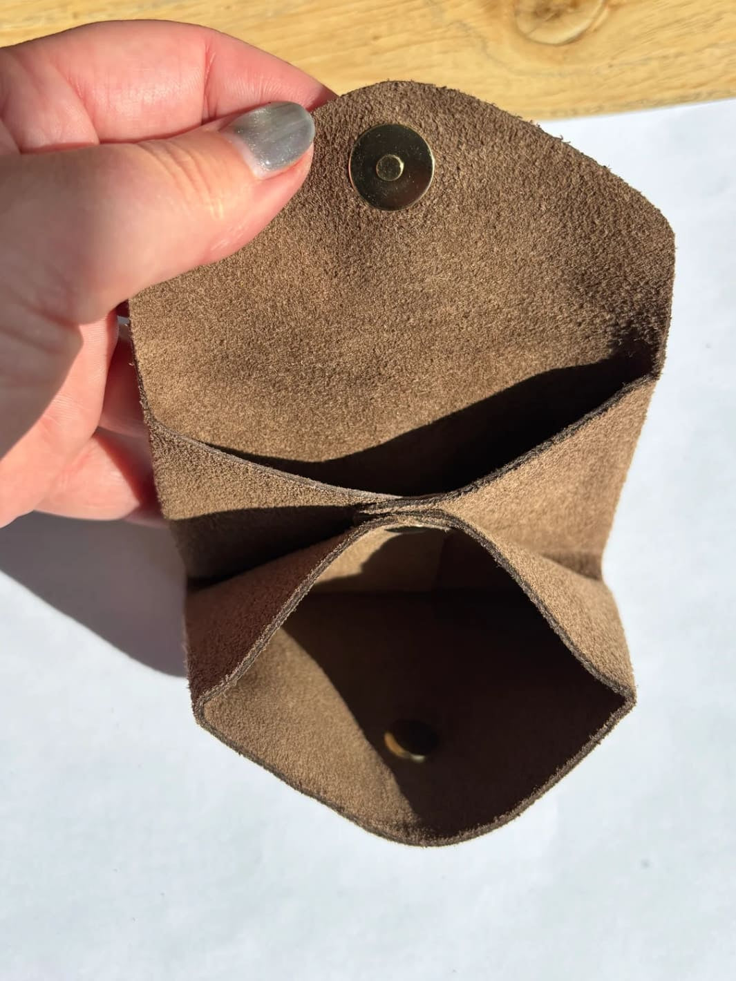 Brown suede coin purse in 'Cool Brown' with a gold button held by hand showing inside of coin purse | Twentyseven Toronto
