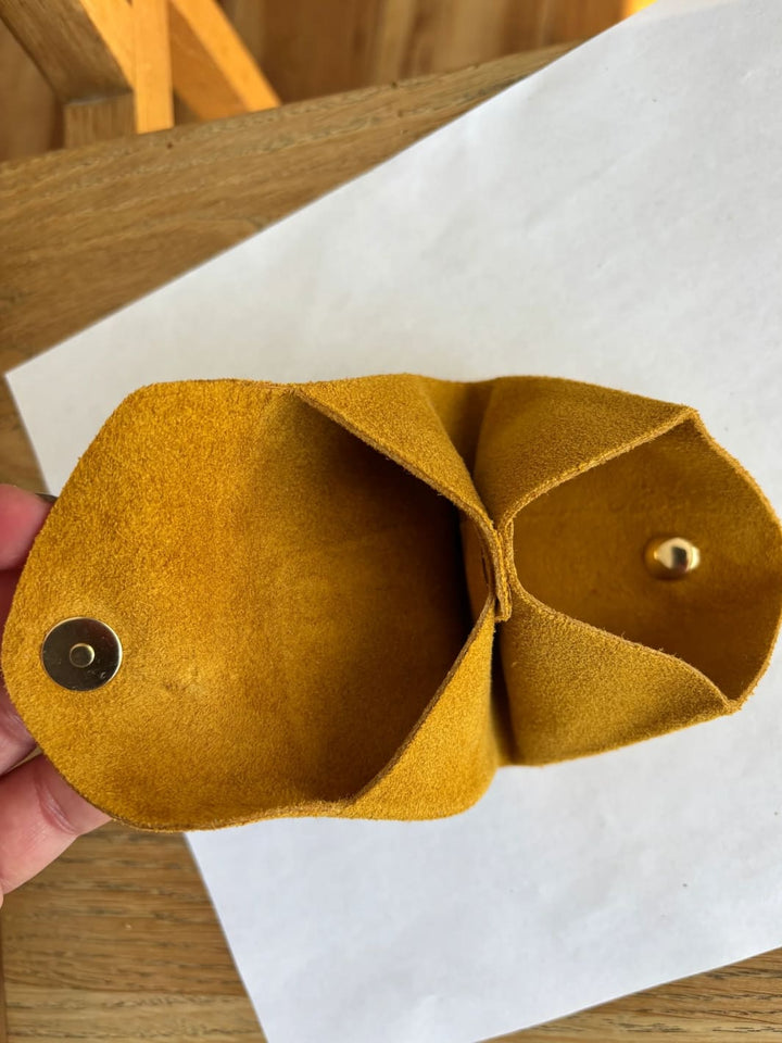 Dark yellow suede coin purse in 'Mustard' with a gold button held by hand showing inside of coin purse | Twentyseven Toronto
