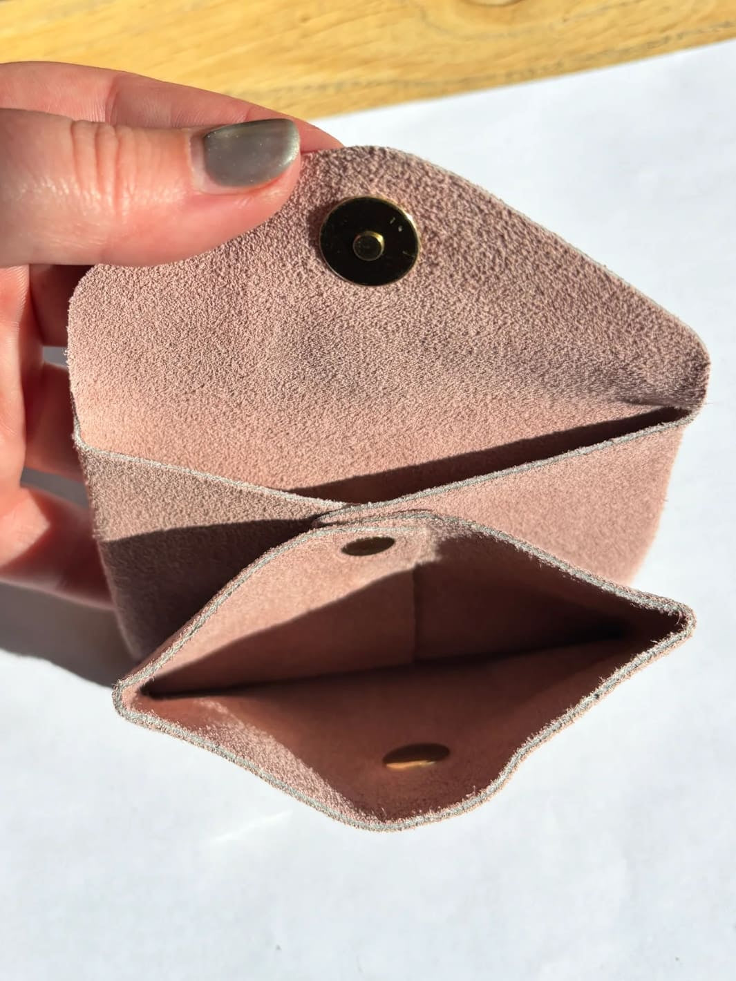 Light pink suede coin purse in 'Rose' with a gold button held by hand showing inside of coin purse | Twentyseven Toronto