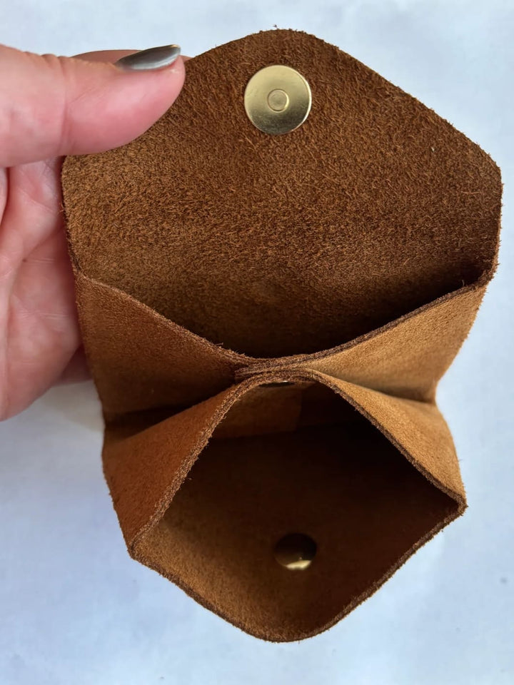 Dark brown suede coin purse in 'Warm Brown' with a gold button held by hand showing inside of coin purse | Twentyseven Toronto