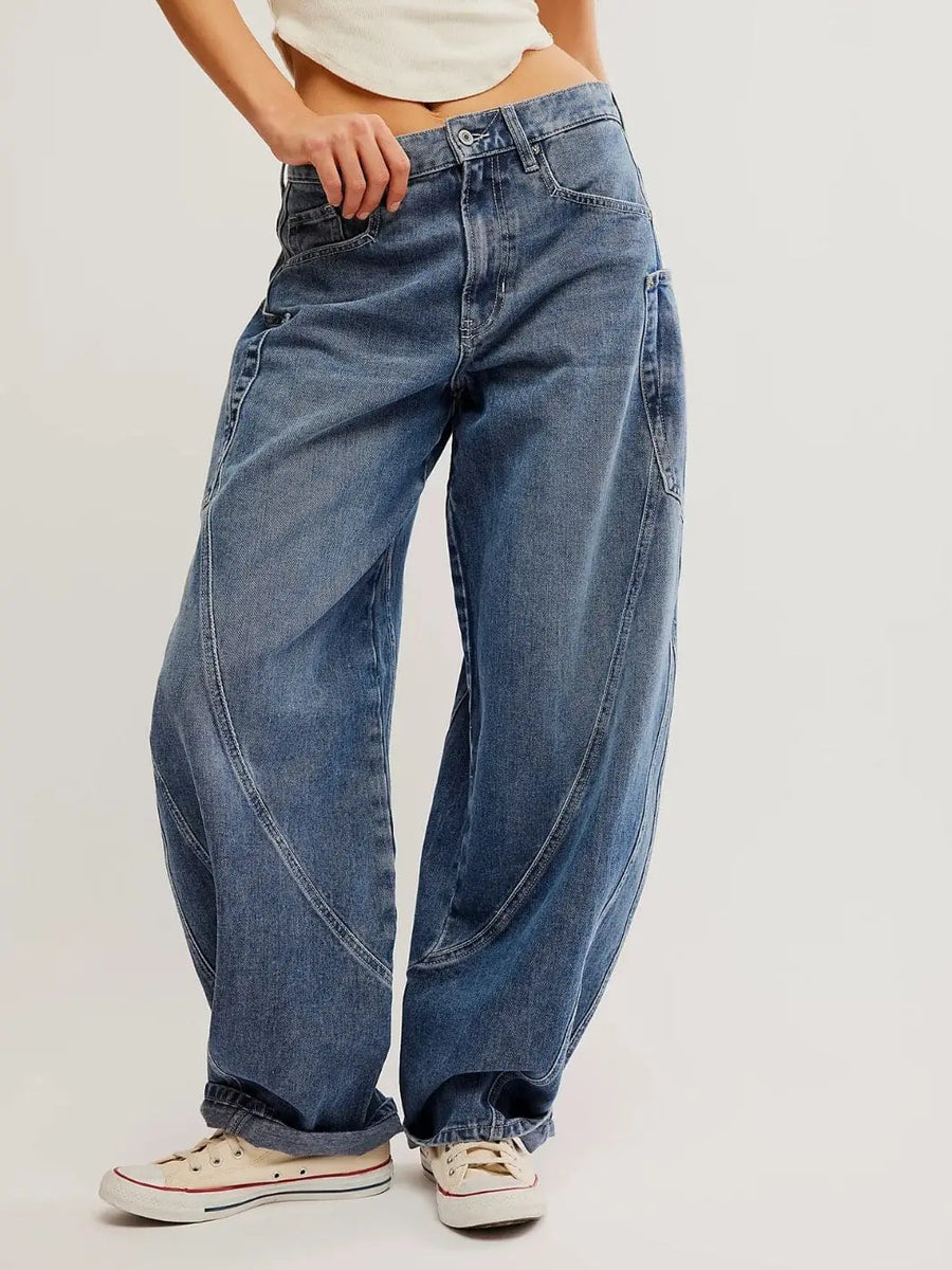 A front view highlights the curved, seamed legs and relaxed silhouette of the Free People Sugar And Spice Barrel Jeans - Beatrix Indigo paired with white sneakers | Twentyseven Toronto