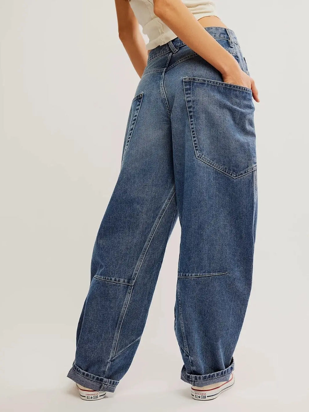 A view from behind shows the loose fit, slouchy back pockets, and cuffed hems of the Free People Sugar And Spice Barrel Jeans - Beatrix Indigo | Twentyseven Toronto