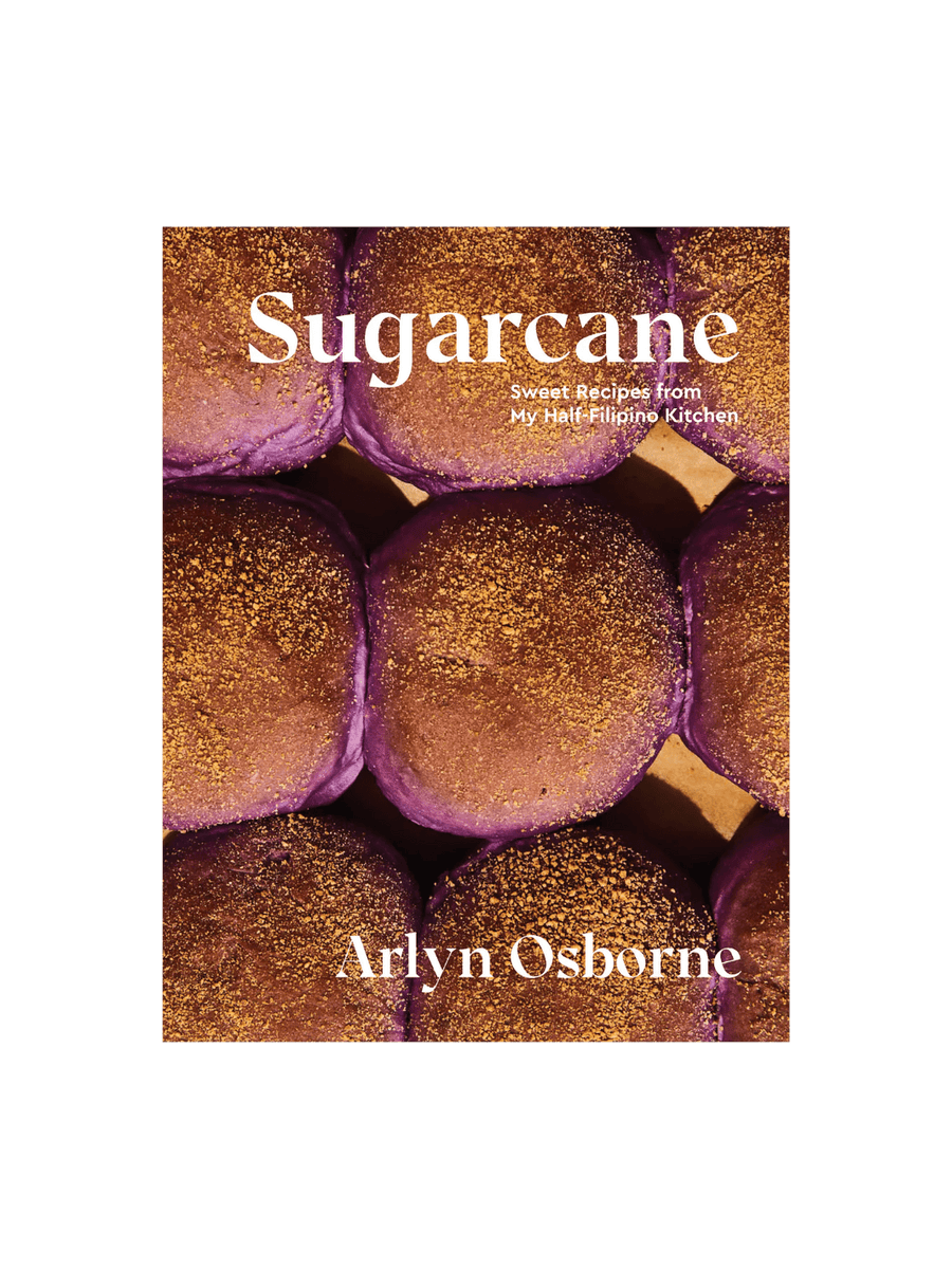 Front cover of the cookbook Sugarcane: Sweet Recipes from My Half-Filipino Kitchen by Arlyn Osborne, featuring a close-up photograph of several round, purple ube buns topped with a golden-brown crumble | Twentyseven Toronto
