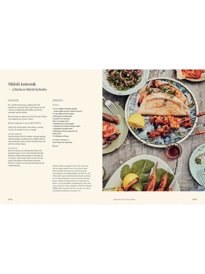 A cookbook spread from Sumac: Recipes and Stories from Syria by Anas Atassi featuring the recipe text for "Shish tawook" on the left and a top-down photograph of grilled chicken skewers served with flatbread and salads on the right | Twentyseven Toronto