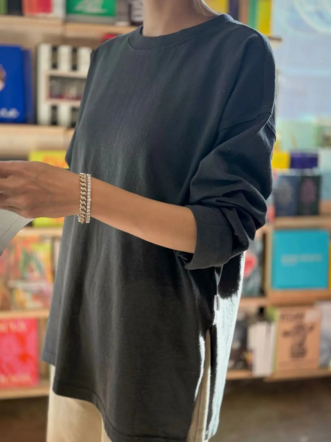 Person wearing a dark gray 'Sunday Tee' oversized sweatshirt from Le Bon Shoppe in a store setting | Twentyseven Toronto