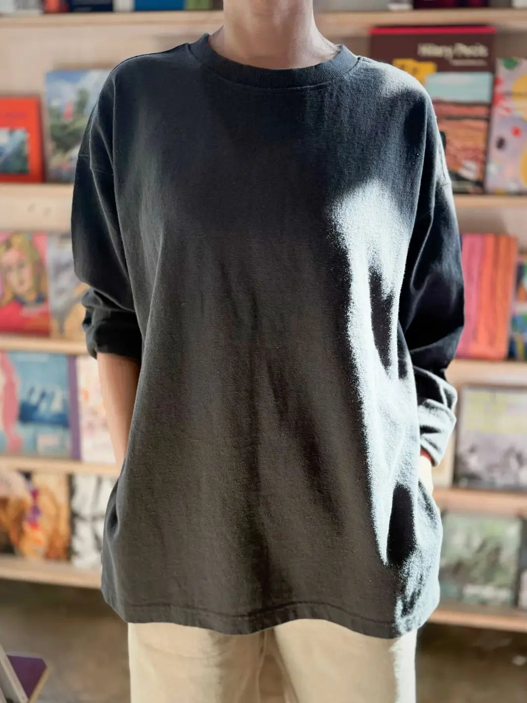 Person wearing a dark gray 'Sunday Tee' oversized sweatshirt from Le Bon Shoppe in a store setting | Twentyseven Toronto