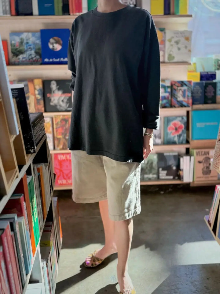 Person wearing a dark gray 'Sunday Tee' oversized sweatshirt and beige shorts from Le Bon Shoppe in a store setting | Twentyseven Toronto