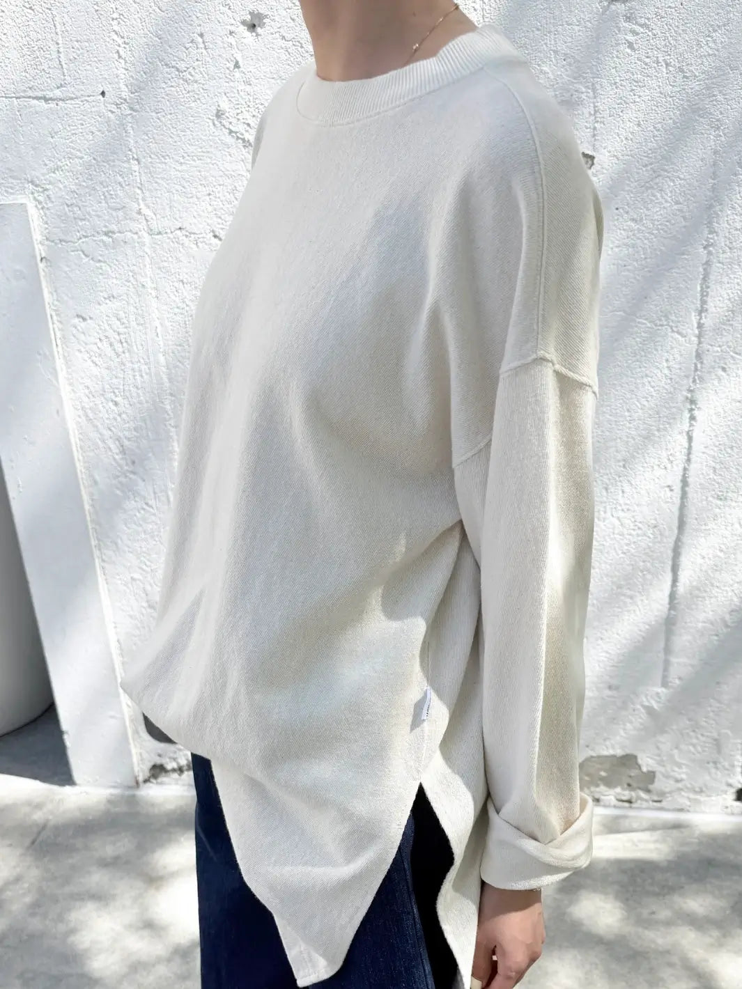 Person wearing an off-white 'Sunday Tee' oversized sweatshirt from Le Bon Shoppe against a plain background | Twentyseven Toronto