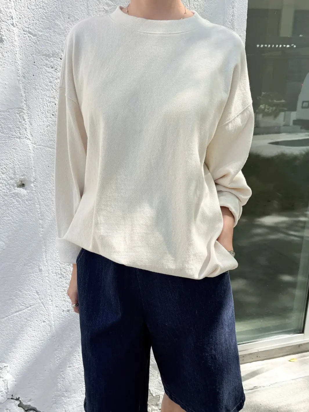 Person wearing a beige 'Sunday Tee' oversized sweatshirt from Le Bon Shoppe in an outdoor setting | Twentyseven Toronto