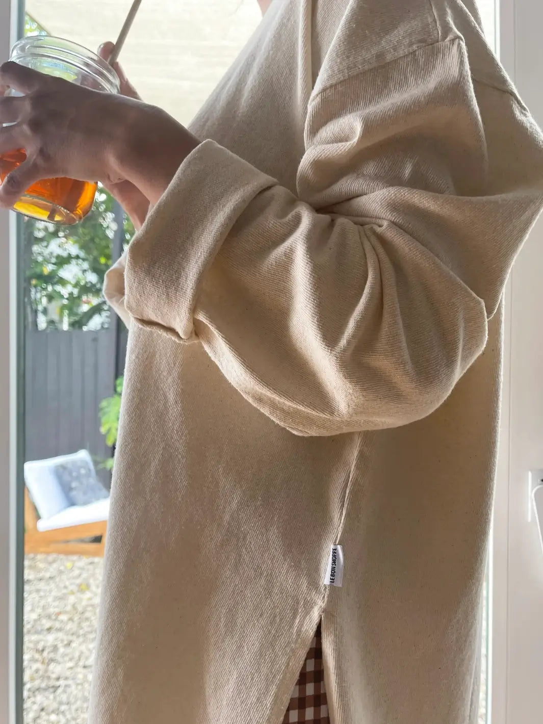 Person wearing a beige 'Sunday Tee' oversized sweatshirt in 'Naturel' from Le Bon Shoppe in against a window | Twentyseven Toronto