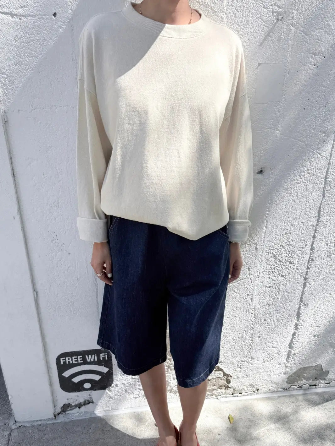 Person wearing a beige 'Sunday Tee' oversized sweatshirt in 'Naturel' from Le Bon Shoppe in against a textured background | Twentyseven Toronto