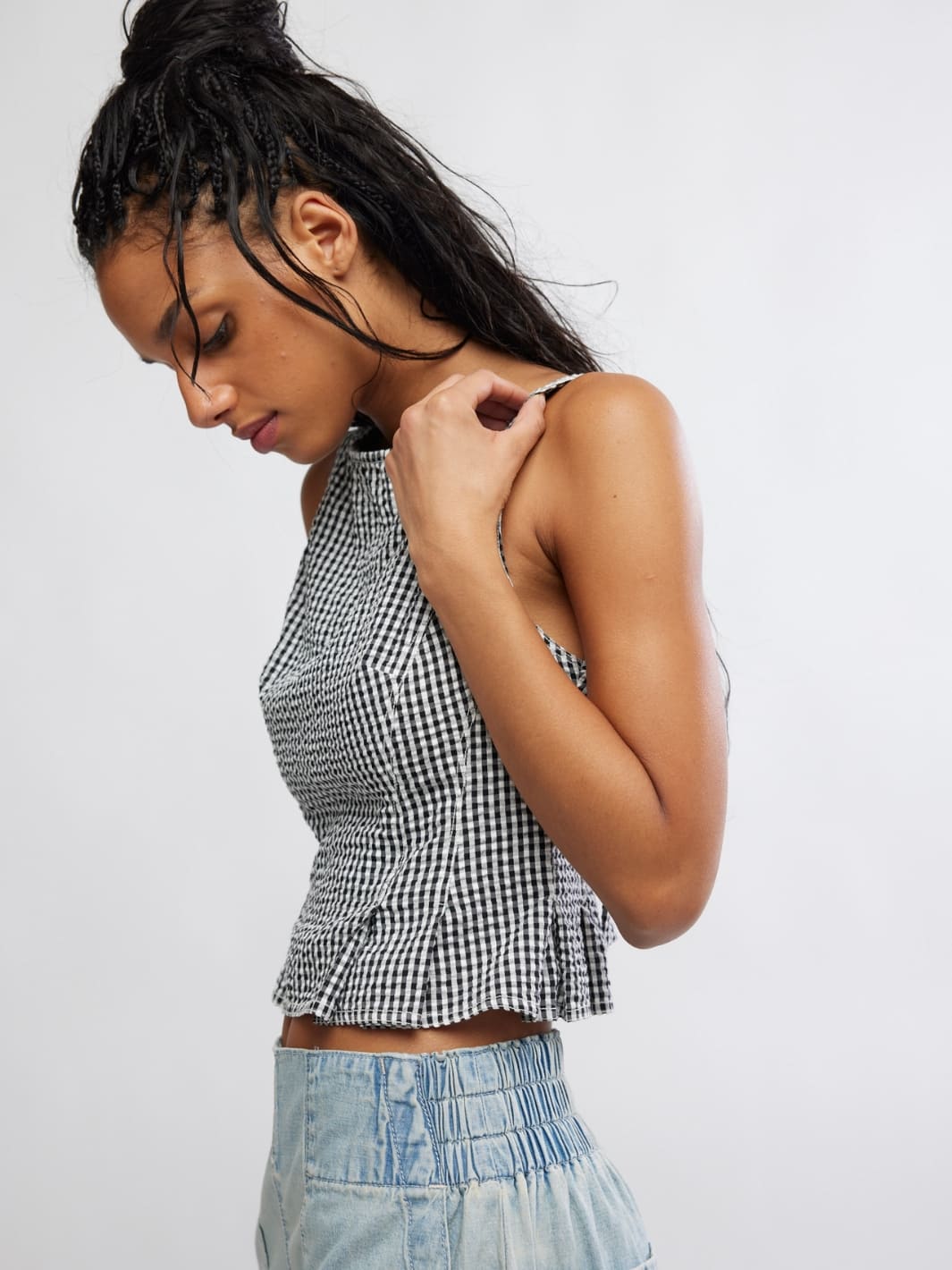 Woman wearing a Free People 'Sunfaded Top' in 'Black and White Combo' checkered top and light blue jeans, side view | Twentyseven Toronto