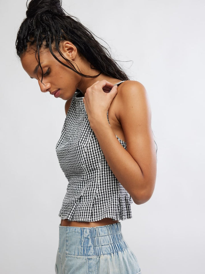 Woman wearing a Free People 'Sunfaded Top' in 'Black and White Combo' checkered top and light blue jeans, side view | Twentyseven Toronto