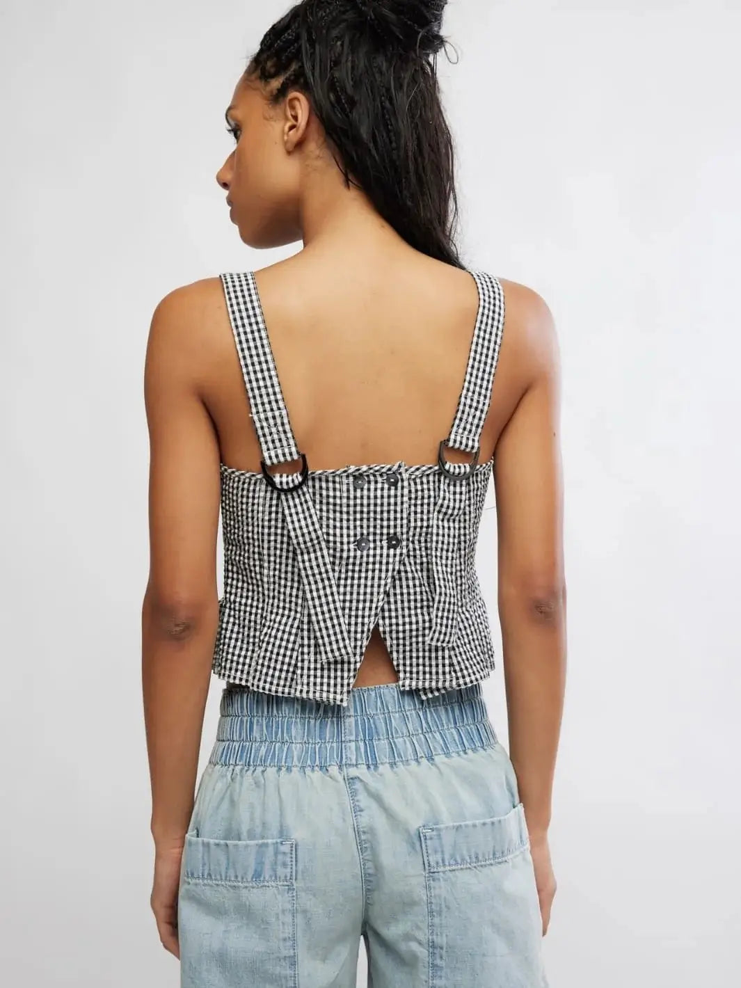 A rear view reveals the open lower-back design, button closures, and D-ring strap adjusters on the Free People Sunfaded Top in Black and White Combo | Twentyseven Toronto