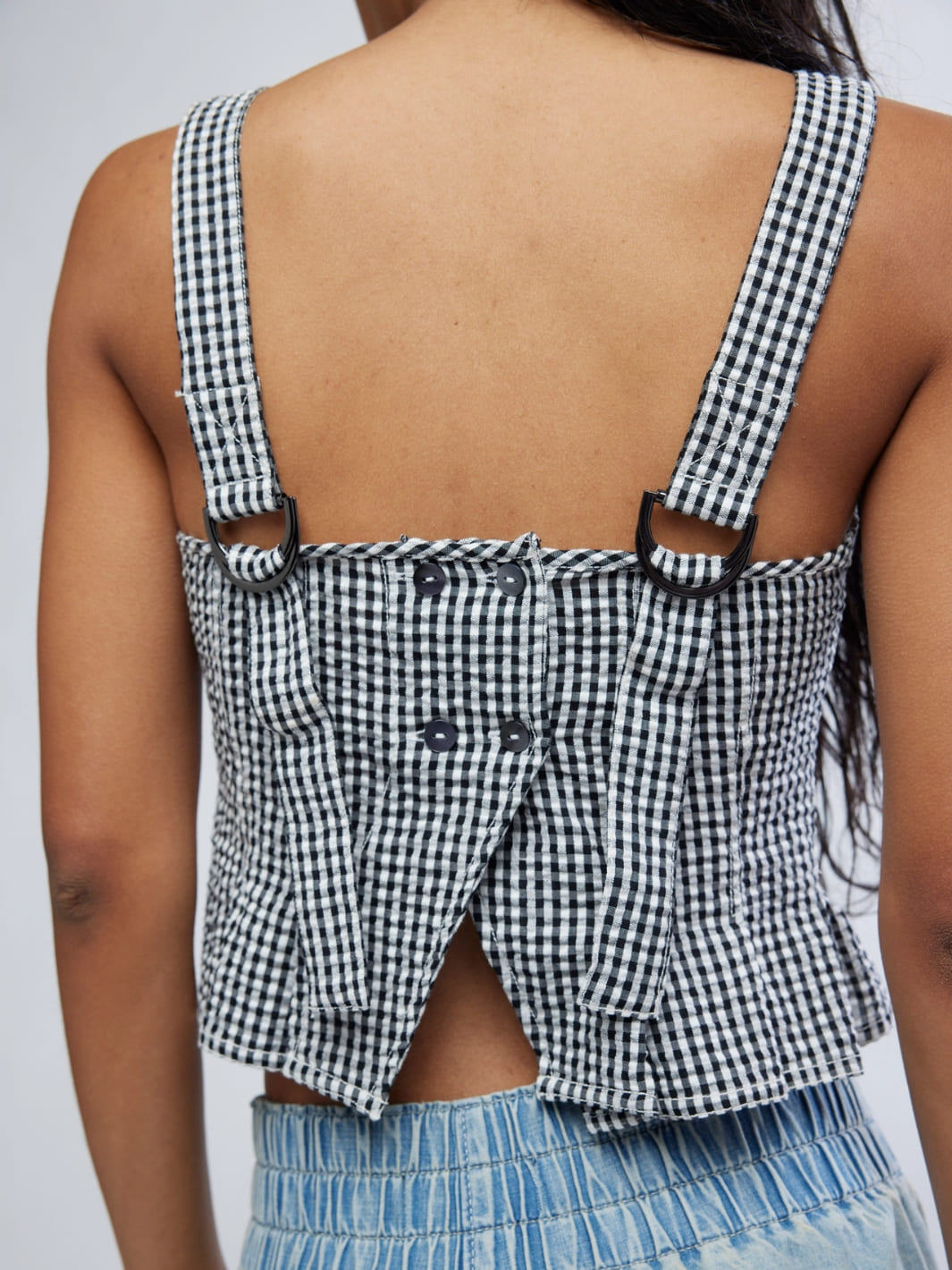 Woman wearing a Free People 'Sunfaded Top' in 'Black and White Combo' checkered top and light blue jeans, back view close up | Twentyseven Toronto