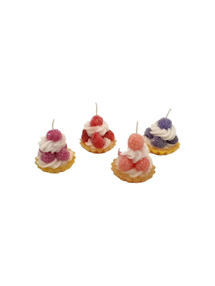Four decorative candles shaped like small tart desserts with whipped cream from  and berries from Cereria Introna on a white background | Twentyseven Toronto