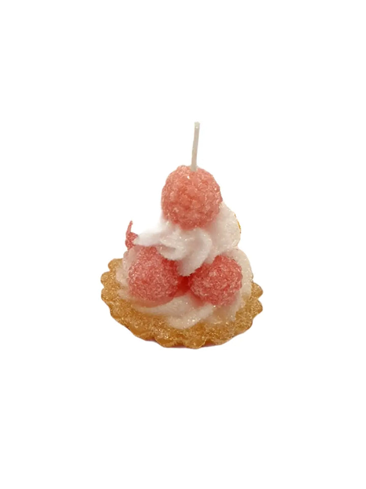 Candle shaped like a tart with white frosting and pink berries from Cereria Introna on a white background | Twentyseven Toronto