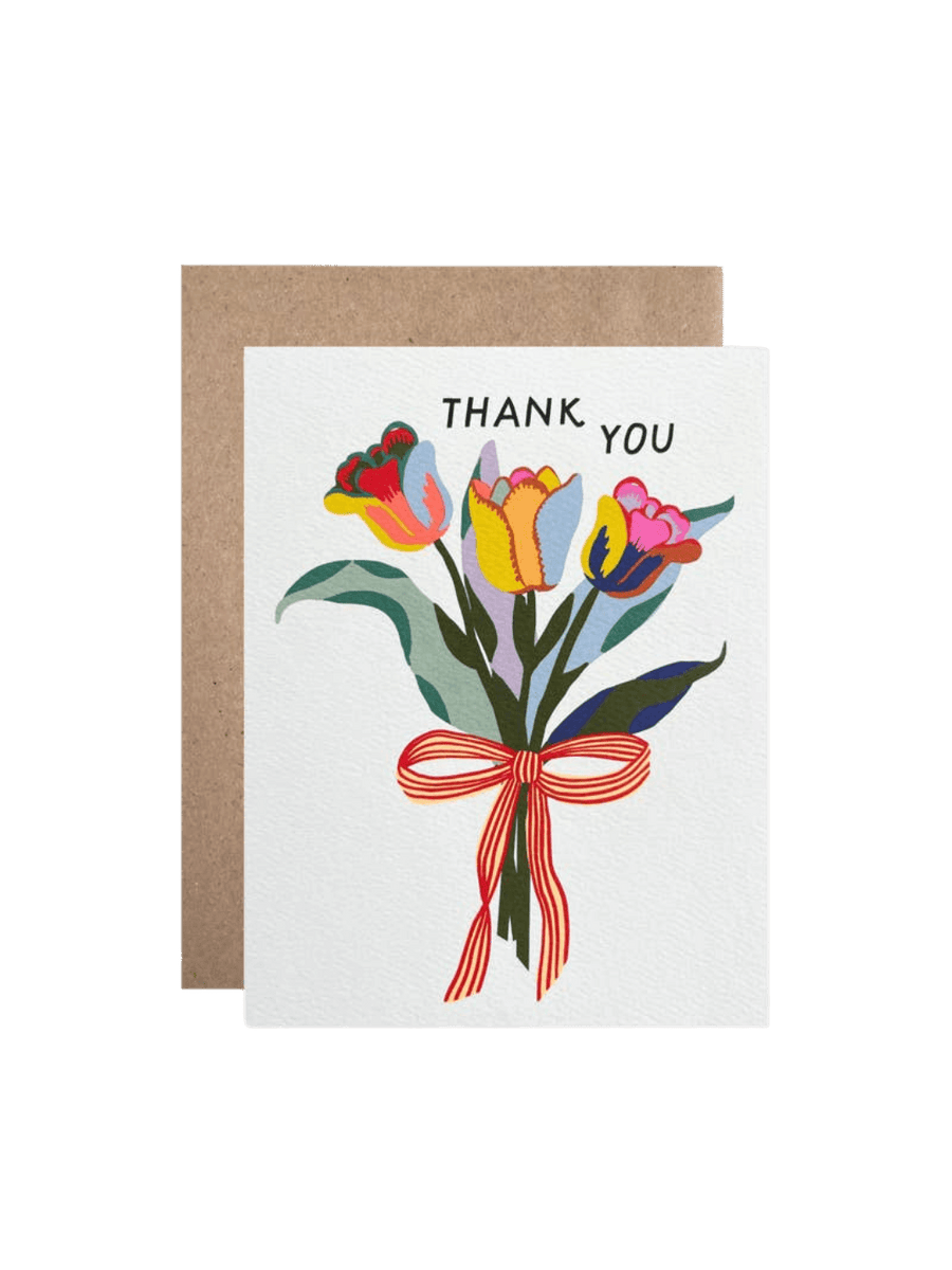 The Hartland Cards Thank You Tulips Card features a hand-illustrated bouquet of three vibrant tulips in shades of red, yellow, blue, and pink, tied with a red-and-yellow striped bow on a white background, with the words "THANK YOU" arched over the flowers, paired with a brown kraft envelope | Twentyseven