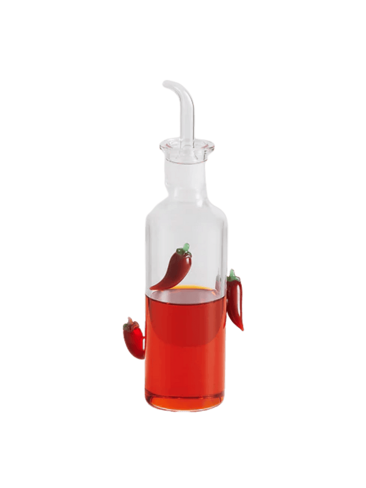 Glass chilli bottle from Maison Balzac with red liquid and decorative chili peppers on a transparent background | Twentyseven Toronto