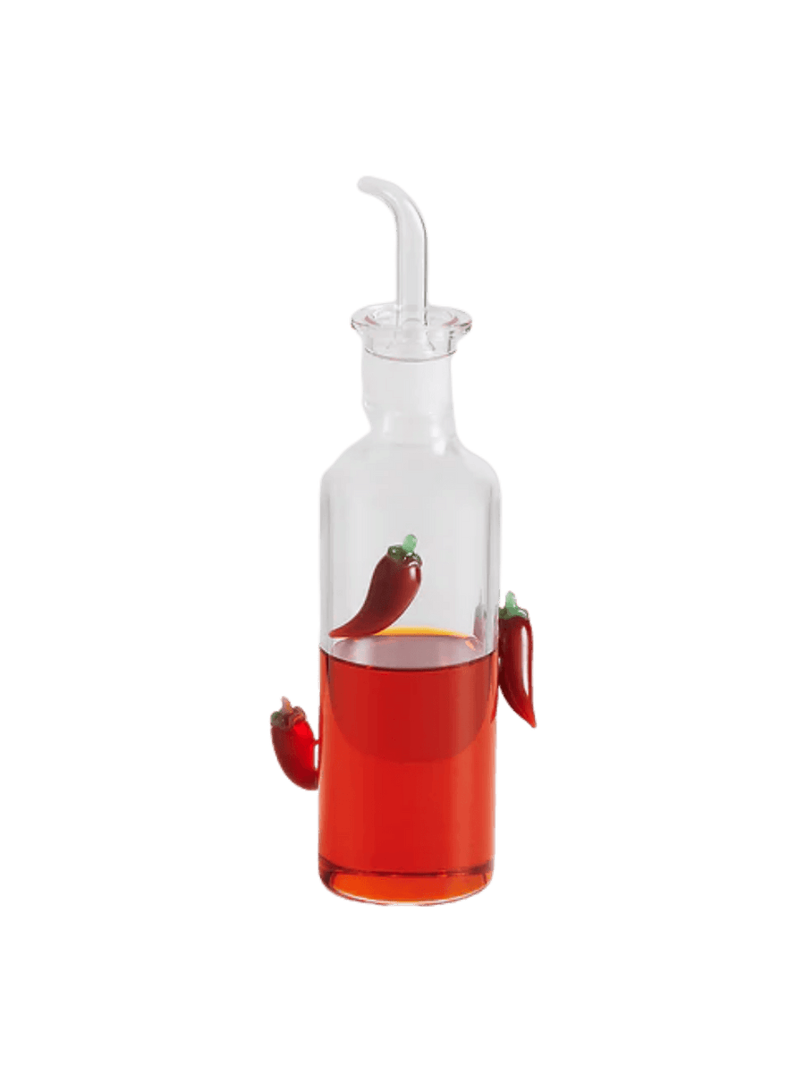 Glass chilli bottle from Maison Balzac with red liquid and decorative chili peppers on a transparent background | Twentyseven Toronto