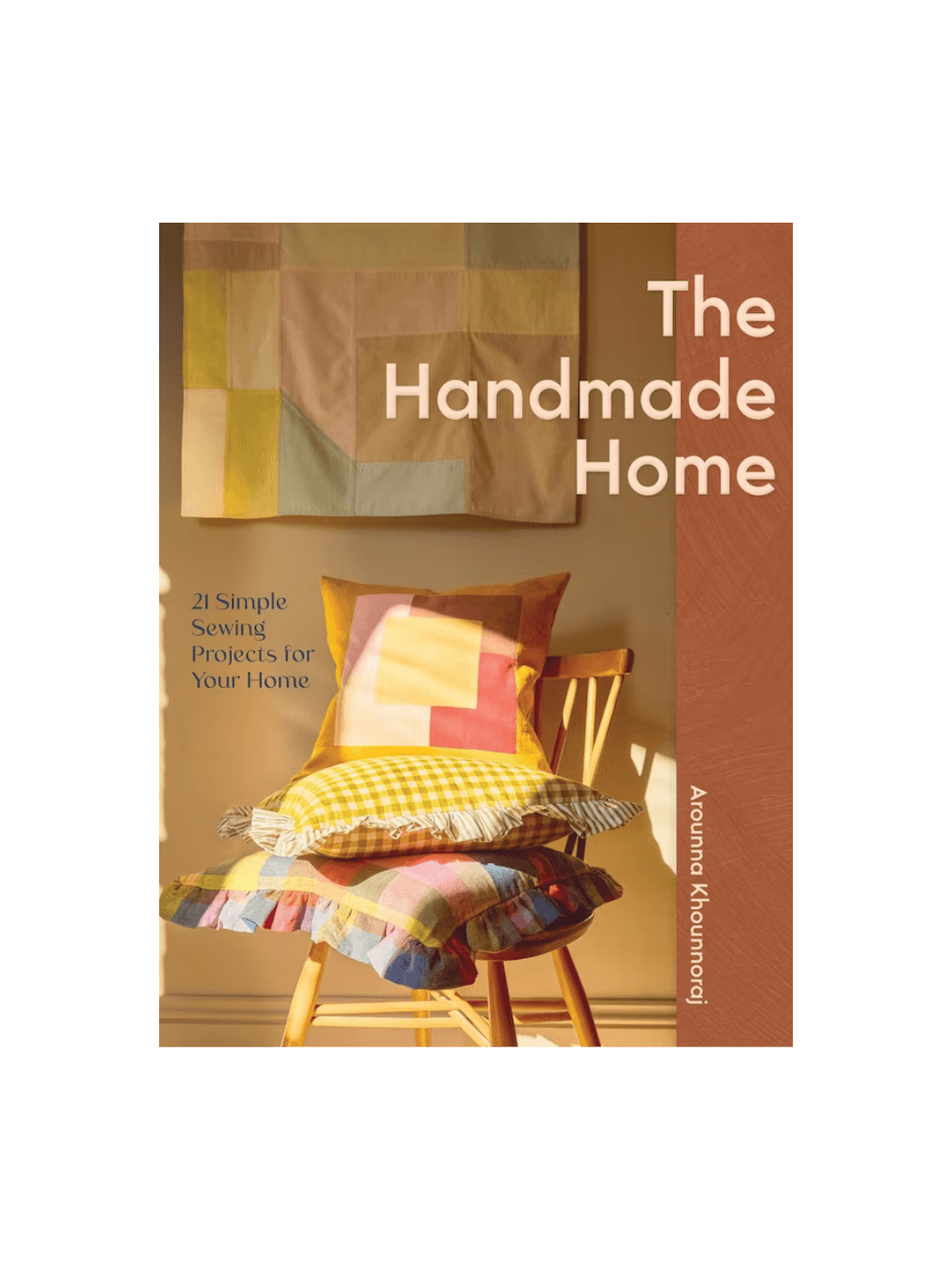 Front cover of the book The Handmade Home by Arounna Khounnoraj, featuring a warm, sunlit interior with a stack of colourful, patterned handmade pillows on a wooden chair | Twentyseven Toronto