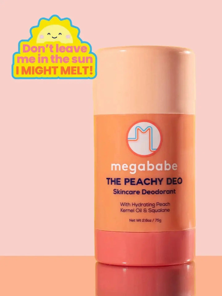 A stick of Megababe The Peachy Deo stands vertically against a soft pink background underneath a yellow sun graphic warning against melting | Twentyseven Toronto