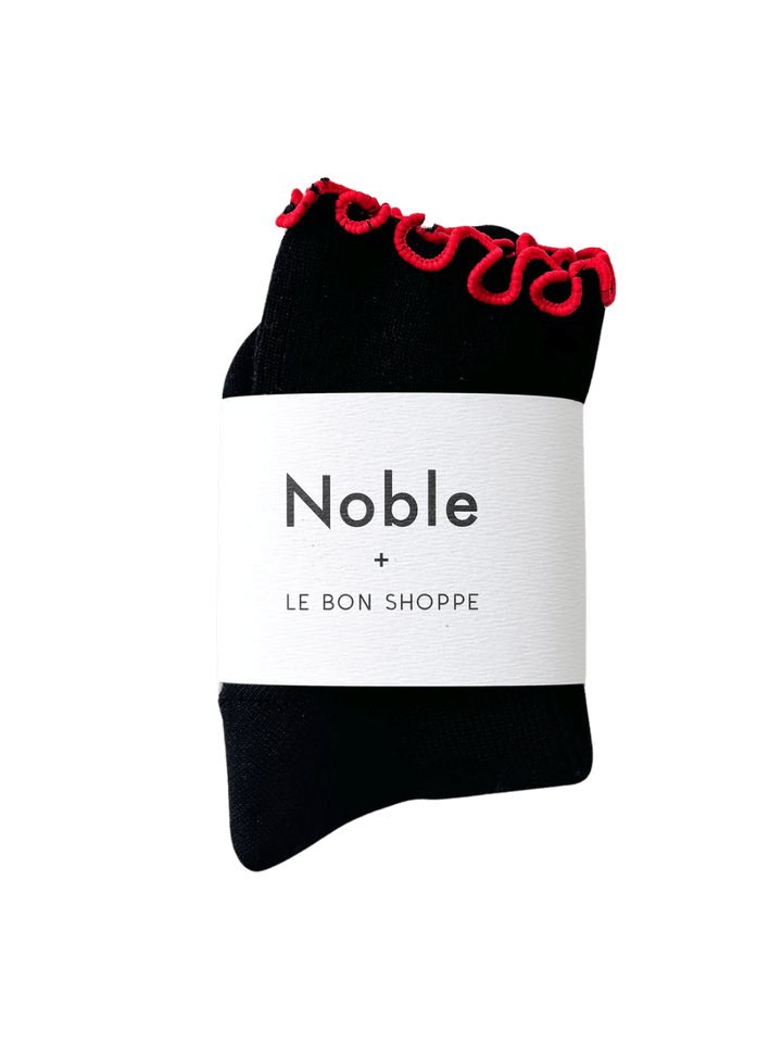A pair of The Petite Ruffled Modal Socks in Black / Red from Le Bon Shoppe is beautifully displayed with its white "Noble + LE BON SHOPPE" collaborative packaging band | Twentyseven Toronto