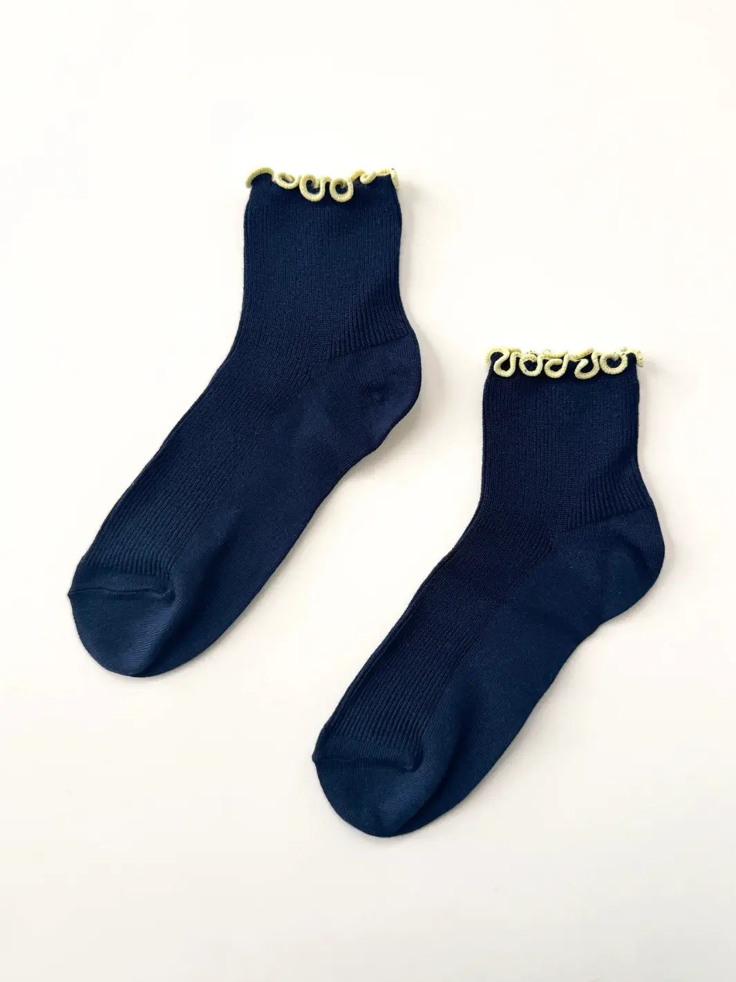 Flat-lay view of a pair of The Petite Ruffled Modal Socks in Butter / Navy from Le Bon Shoppe against a clean white background | Twentyseven Toronto