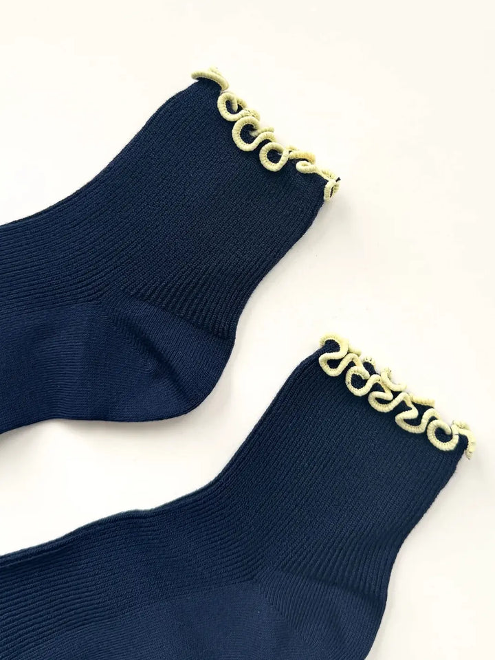 Detailed close up shot of the ribbed knit texture and contrasting wavy trim of The Petite Ruffled Modal Socks in Butter / Navy from Le Bon Shoppe | Twentyseven Toronto
