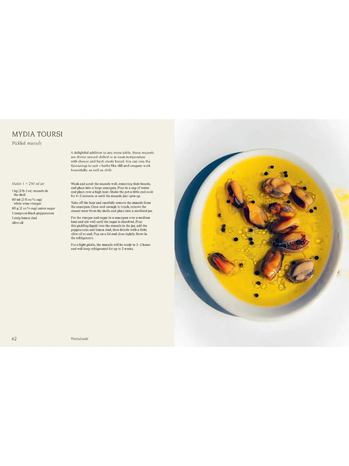 Recipe page from Thessaloniki: And the Many Kitchens of Northern Greece by Meni Valle for Mydia Toursi (Pickled mussels), showing a white bowl filled with mussels submerged in olive oil infused with black peppercorns | Twentyseven Toronto