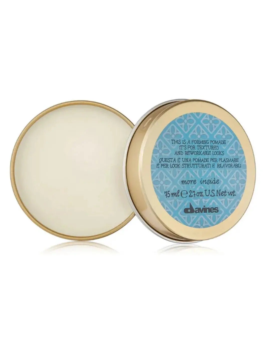 An open gold metal tin of Davines This is a Forming Pomade rests on a reflective white surface, showing the pomade product inside next to its light blue patterned lid | Twentyseven Toronto