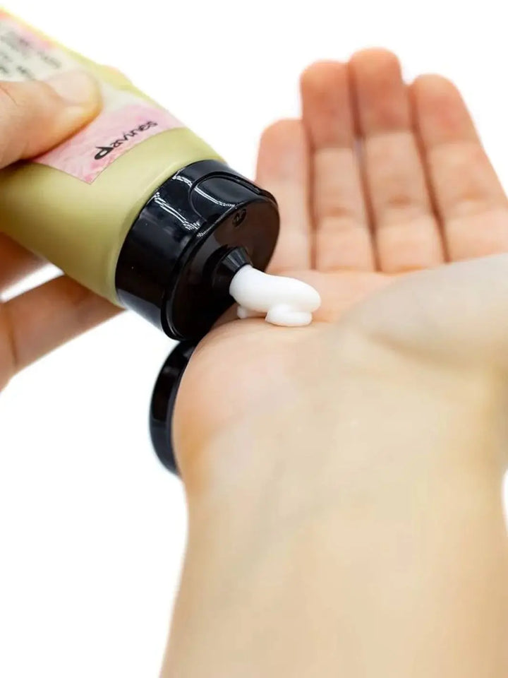 A thick dollop of white cream is squeezed from an olive green tube of Davines This is a Medium Hold Pliable Paste onto an open hand | Twentyseven Toronto