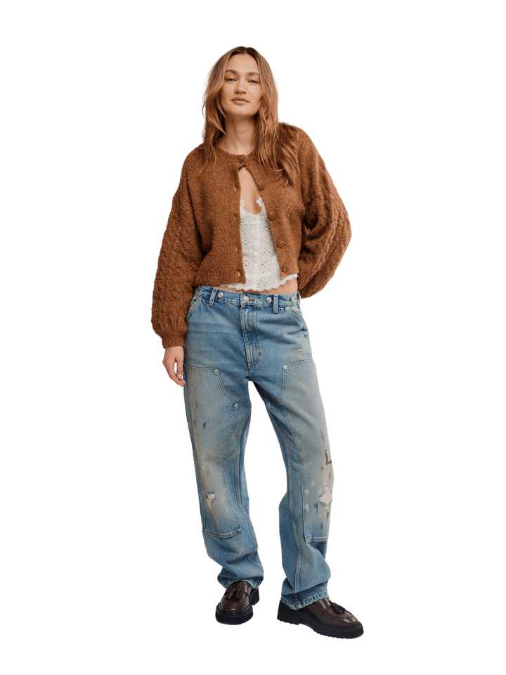 A model stands wearing a brown fuzzy cropped Thistle Cardi in Macadamia from Free People over a white top, light-wash distressed blue jeans, and dark brown leather shoes | Twentyseven Toronto