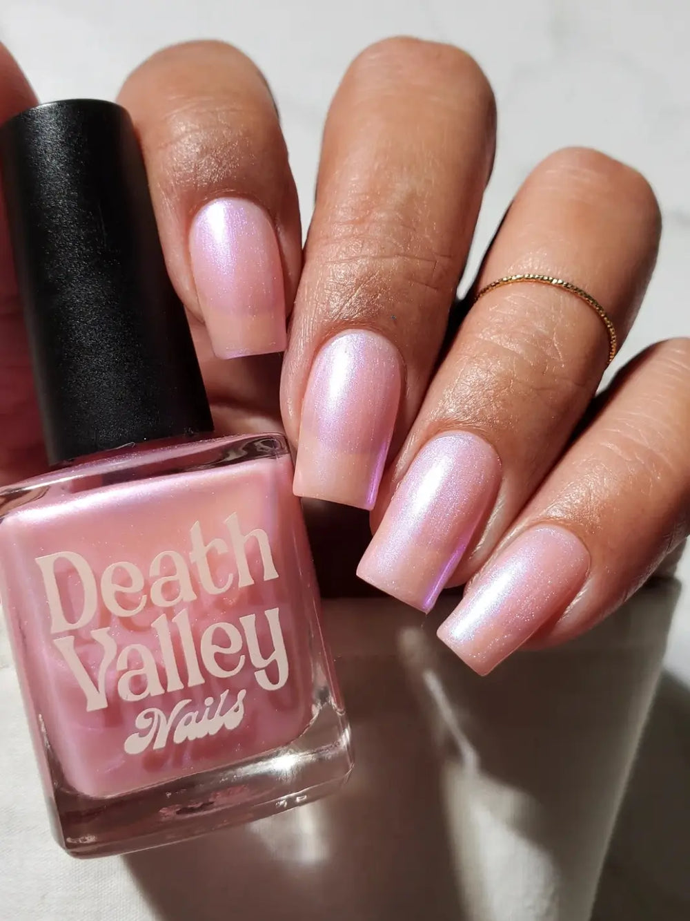Manicured pink square nails next to a bottle of Death Valley Nails Throwing Spaghetti At The Wall Of Your Heart To See What Sticks Nail Polish | Twentyseven Toronto