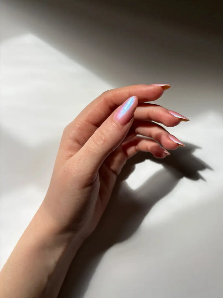 A hand with a fair skin tone and long, almond-shaped nails curves gently underf sunlight, showing off the intense blue-to-purple shimmer of Death Valley Nails Throwing Spaghetti At The Wall Of Your Heart To See What Sticks Nail Polish | Twentsyeven Toronto