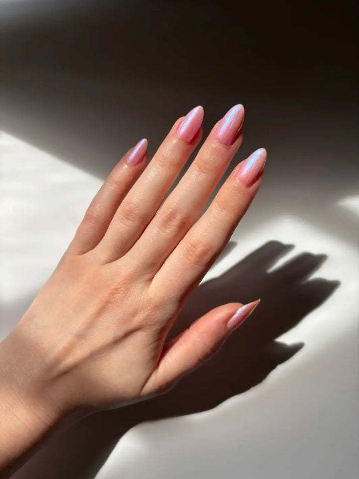 A hand with long, elegant nails featuring a shimmering pink coat of Death Valley Nails Throwing Spaghetti At The Wall Of Your Heart To See What Sticks Nail Polish | Twentyseven Toronto