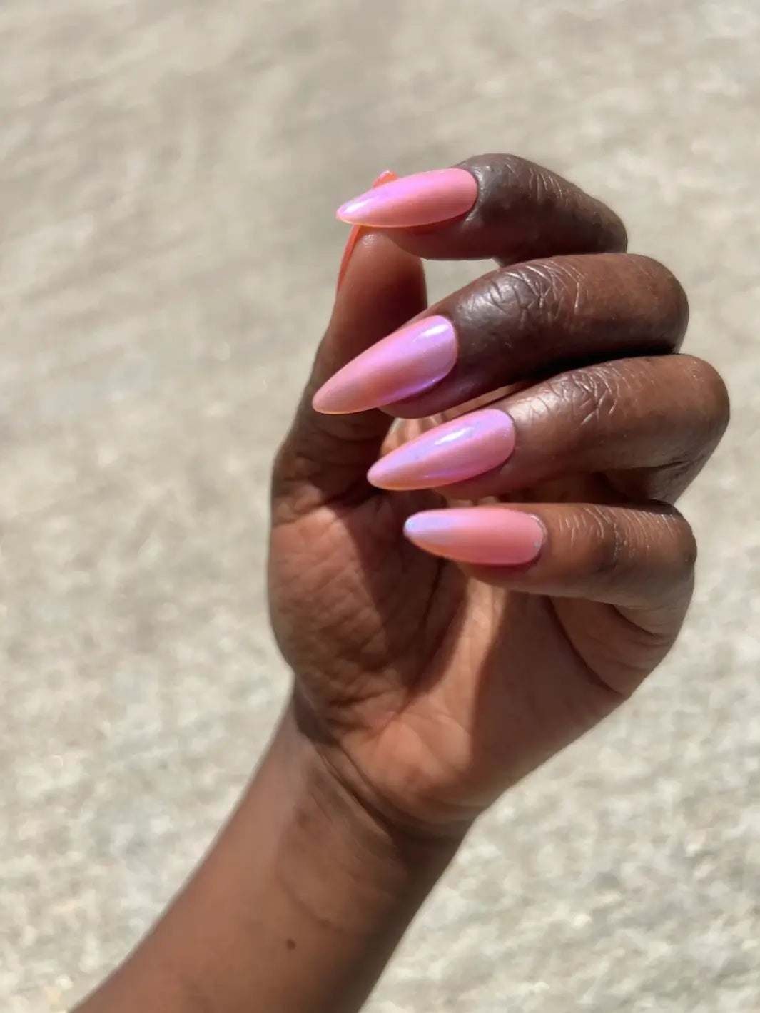 A hand with deep skin tone showing an iridescent pink manicure using Death Valley Nails Throwing Spaghetti At The Wall Of Your Heart To See What Sticks Nail Polish | Twentyseven Toronto