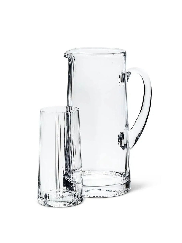 An empty, clear glassware set featuring an Abbott Collection Tight Optic Jug with a smooth handle alongside a matching ribbed highball glass against a solid white background | Twentyseven Toronto