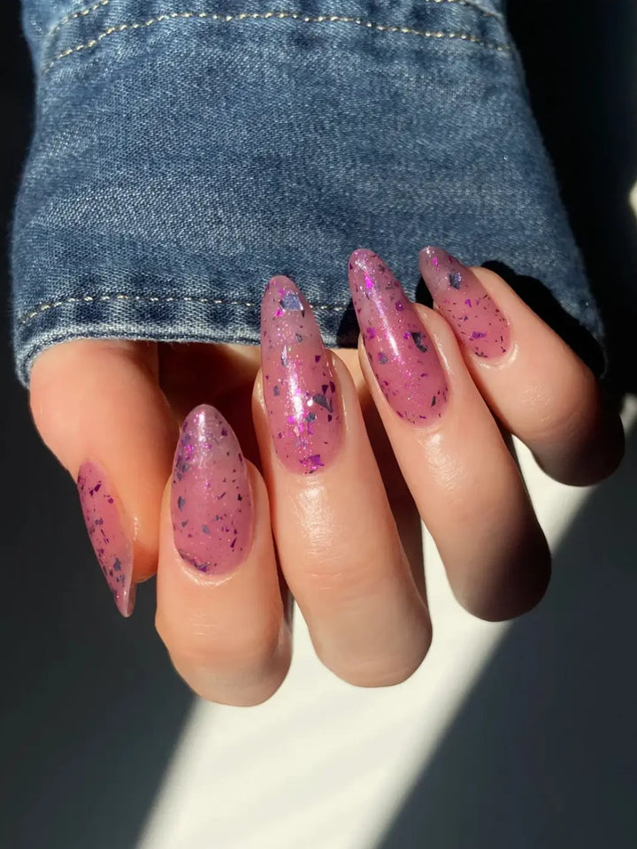 Hand with long glittery pink nails using 'Till Death Do Us Part' nail polish by Death Valley Nails wearing a denim sleeve | Twentyseven Toronto