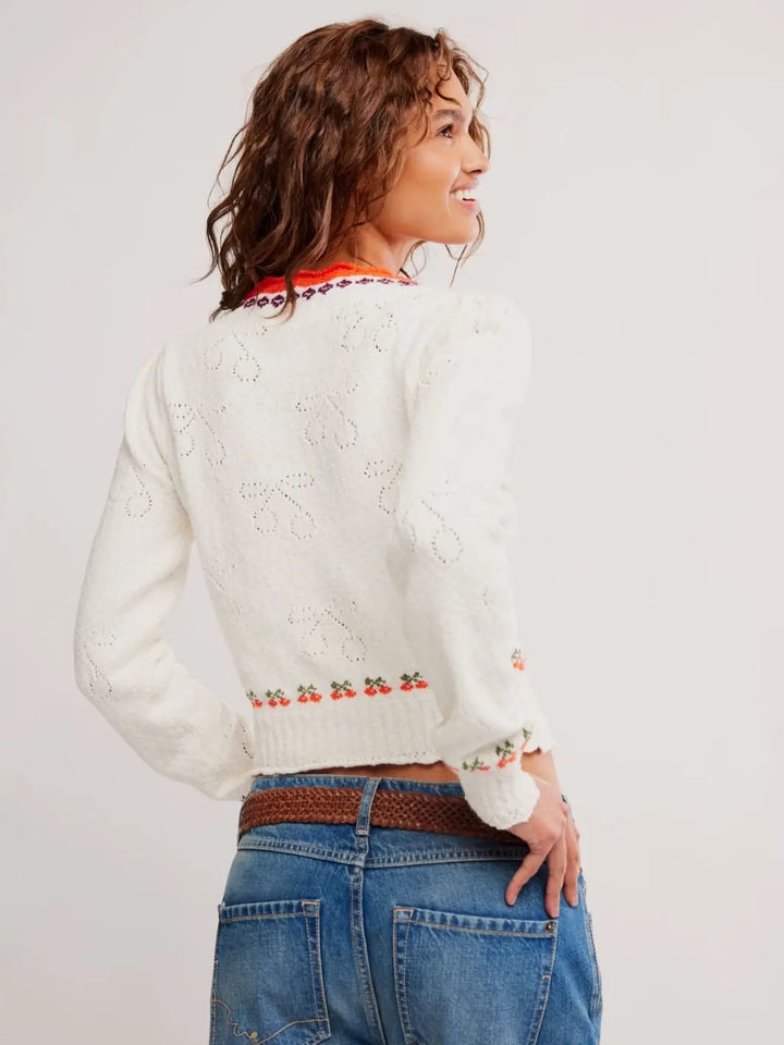 Woman wearing a white sweater red trim from Free People Tilly Pullover in 'Coconut Milk Combo' and blue jeans on a white background | Twentyseven Toronto