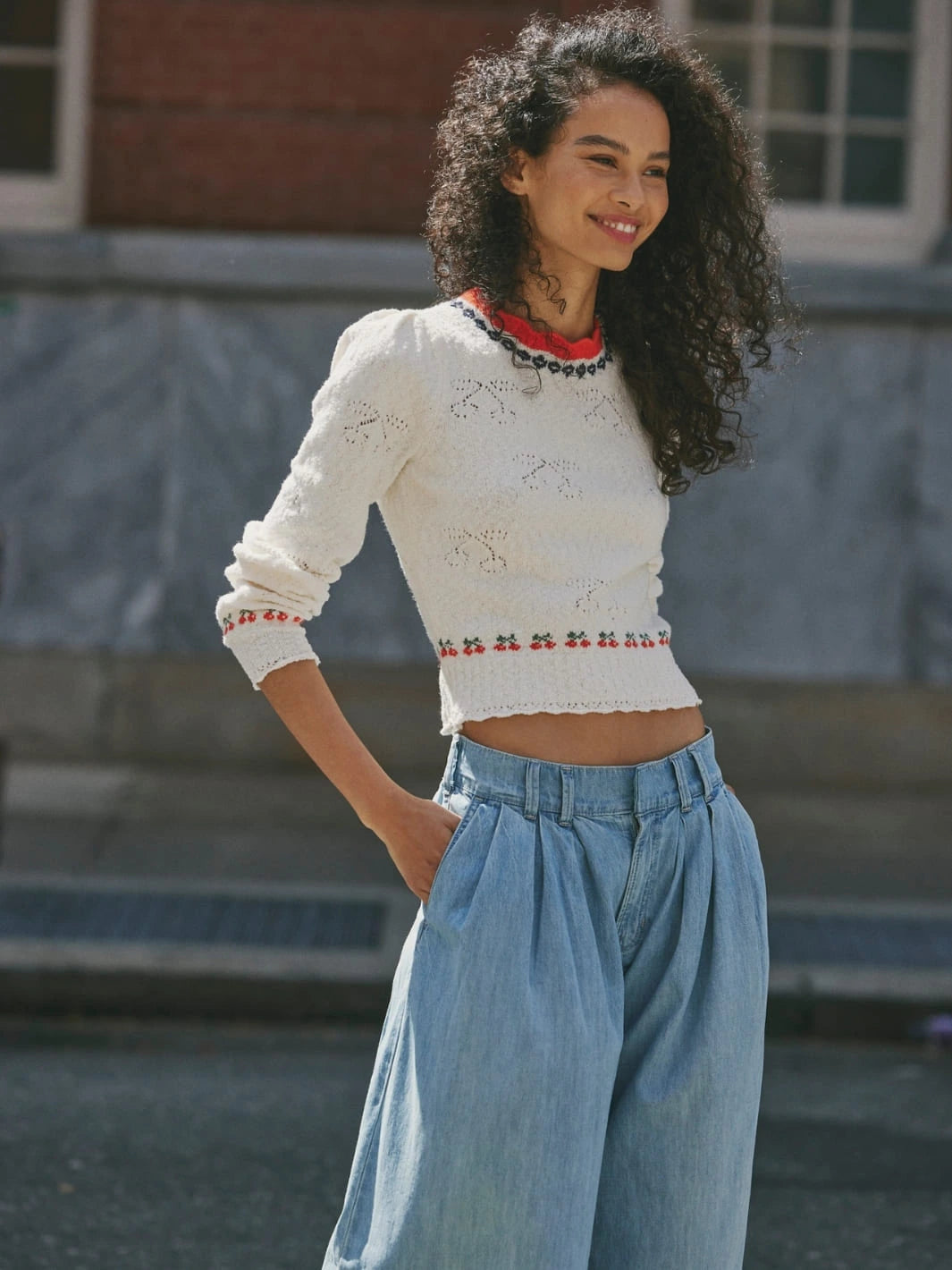 Woman wearing a white Tilly Pullover in 'Coconut Milk Combo' sweater from Free People and blue jeans standing outdoors | Twentyseven Toronto