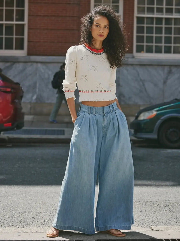 Woman wearing a white sweater from Free People in Tilly Pullover 'Coconut Milk Combo' and blue wide-leg jeans on a street | Twentyseven Toronto