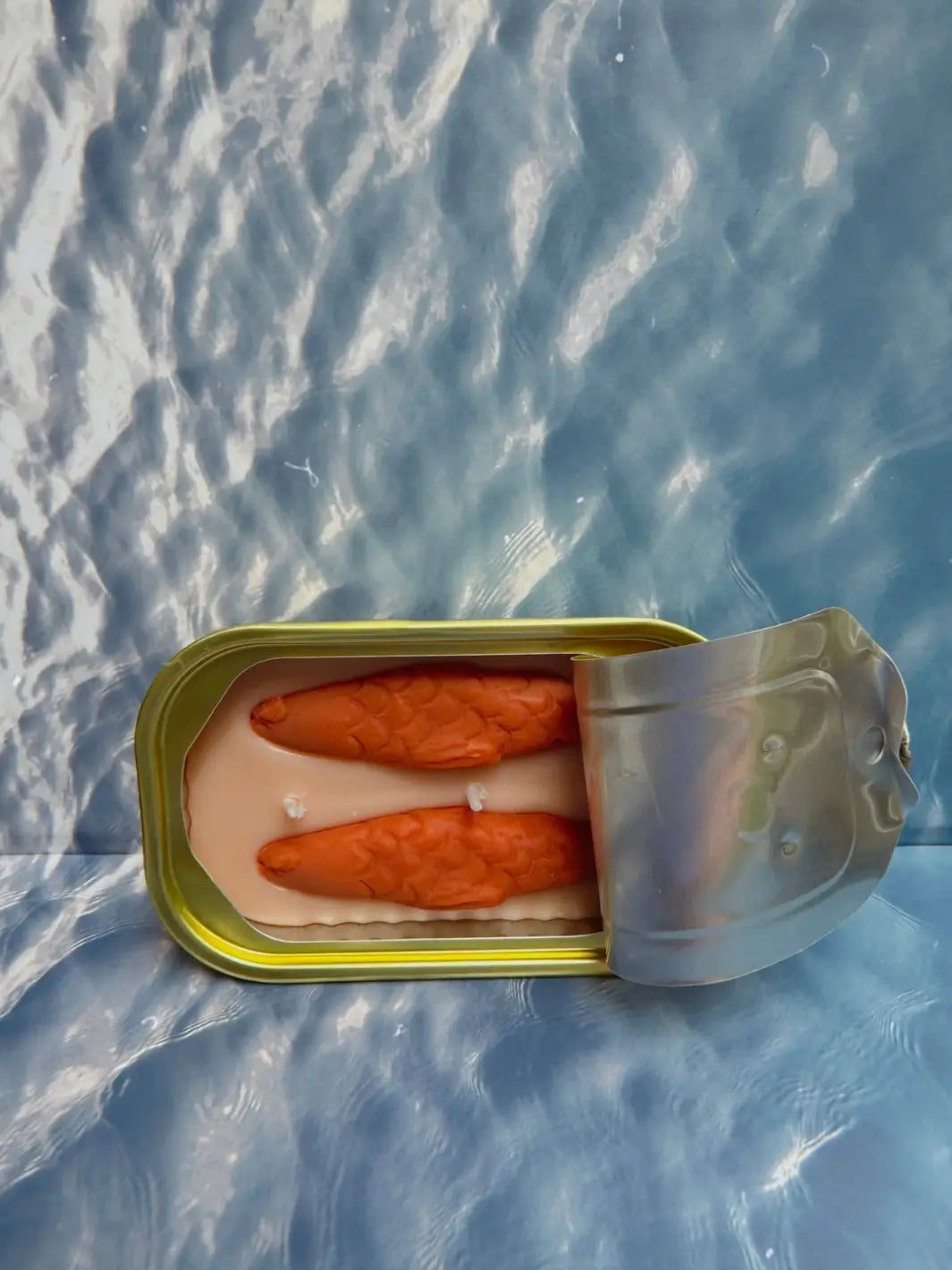 Open tin of Tinned Fish Candle with 'Oakmoss and Amber' scent on a blue background | Twentyseven Toronto
